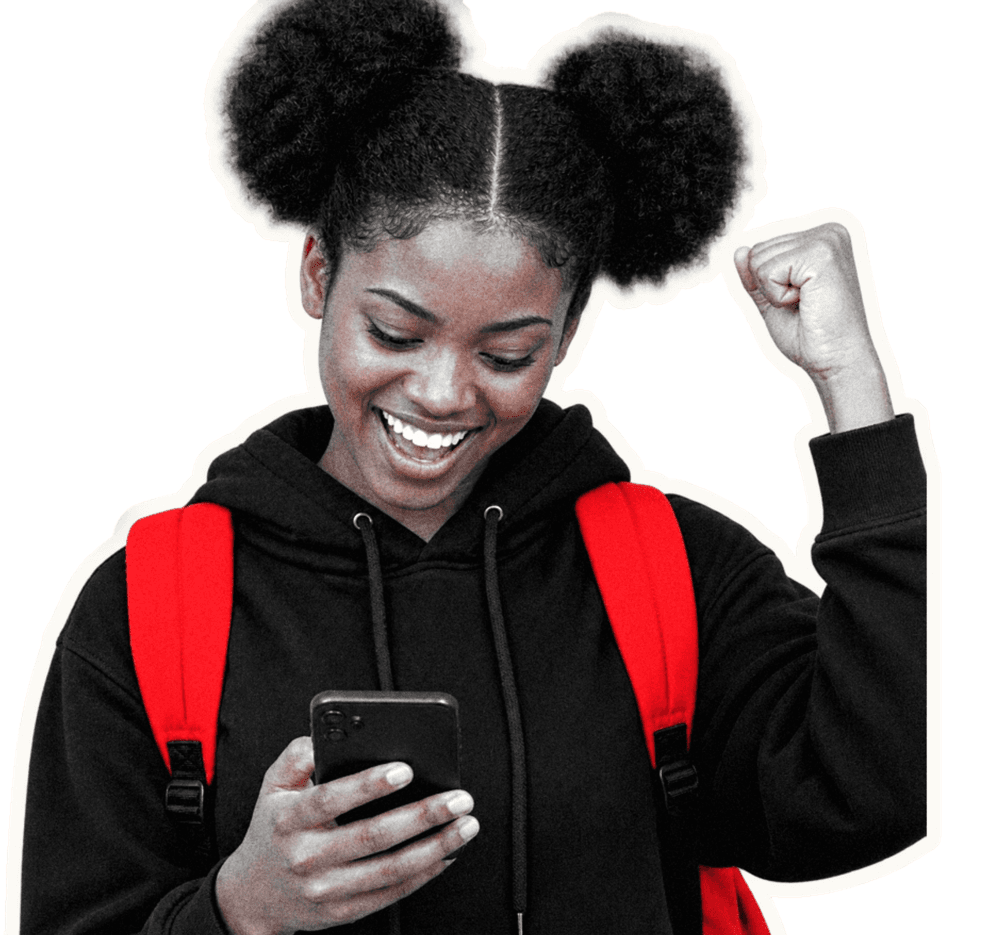 A student smiling at her phone with her fist in the air